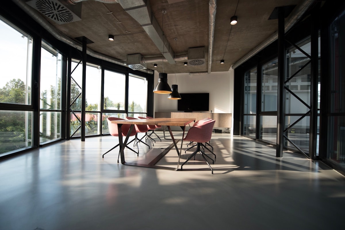 Sala de reunião com mesa de madeira e grandes vãos de vidro